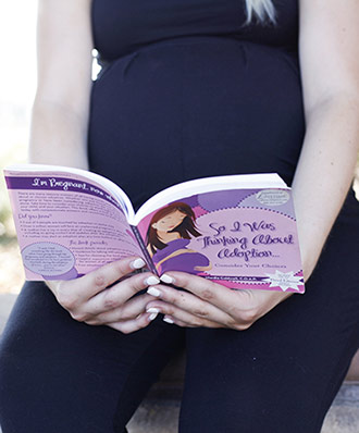 Pregnant woman reads the book So I Was Thinking About Adoption