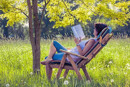 Woman reading a book outside to practice self-care