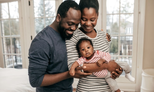 Happy adoptive couple at home with their baby after following tips to afford adoption
