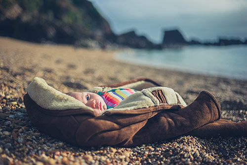 Abandoned baby laying in an adult's coat on a seashore