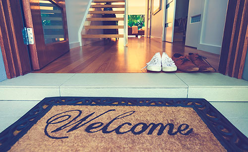 Welcome mat with two pairs of shoes in the entryway of home